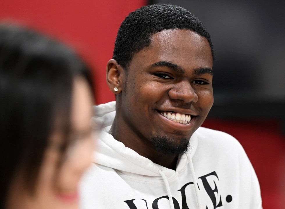 A student sits at a table smiling